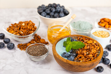 Granola bowl with yogurt and fresh almonds, blueberries, raspberries,peach and strawberries on a marble kitchen table.Acai and spirulina bowl.Healthy breakfast concept.copy space.Place for text.