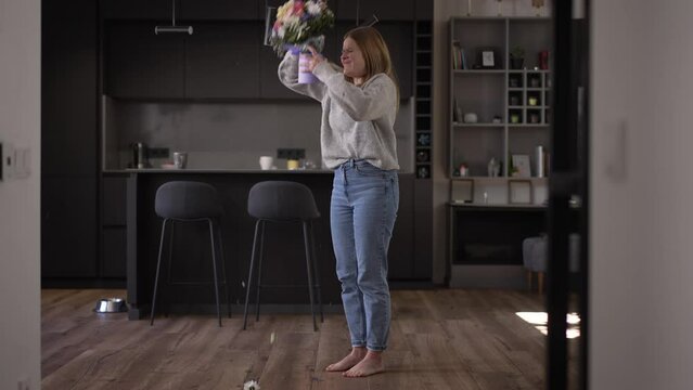 Wide shot furious angry young woman breaking bouquet of flowers and looking at camera with desperate facial expression. Portrait of hopeless frustrated Caucasian lady posing after breakup