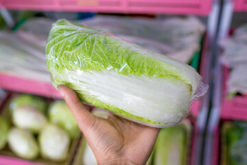 Fresh green cabbage, chinese cabbage in a supermarket. Selective focus on the head.