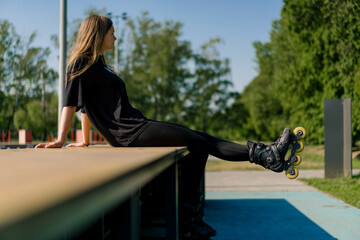 sporty girl after rollerblading rests on the sports ground thoughtful and happy with the street sports lesson