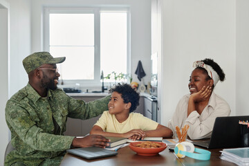 Family happy to see their father returning from war, they sitting at table in the kitchen and talking to each other