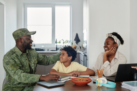 Family happy to see their father returning from war, they sitting at table in the kitchen and talking to each other - Powered by Adobe