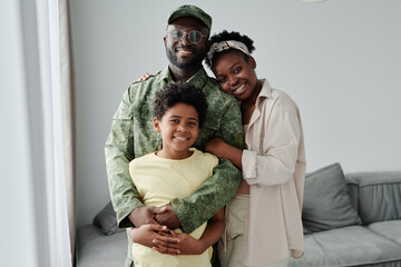 Portrait of happy African American family of three smiling at camera, they meeting their dad from war