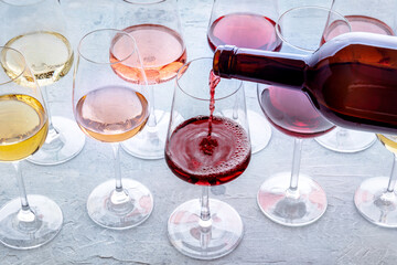 Red wine pour into a glass at a tasting. Rose, red, and white wine, drinks on a table at a winery....