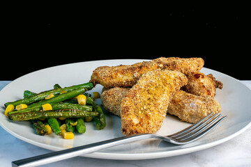 chicken tenders served  with sauteed green beans  peas and corn,
