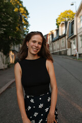 Fototapeta premium Smiling young woman standing on a calm neighbourhood road in Helsinki, Finland