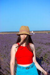Happy slim stylish woman in straw hat, blue jeans Female portrait on lavender field. Traveling to nature on summer vacation. Travel in spring to Provence, France. Happy girl in red top Happy traveller