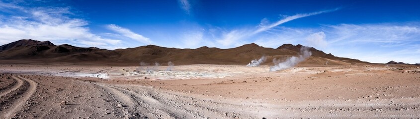 Fototapeta na wymiar Stunning geothermic field of Sol de Mañana with its steaming geysers and hot pools with bubbling mud - just one sight on the lagoon route in Bolivia, South America - Panorama