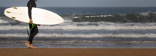 surfer walking on the beach with the surfboard