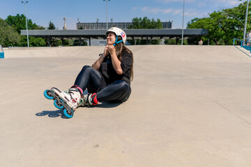 upset girl rollerblading on roller drome takes off protective helmet active recreation skating...