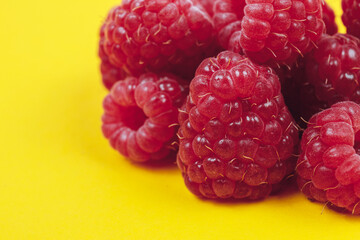 Heap of fresh ripe and sweet raspberries on yellow background. Red raspberries. Macro shot.