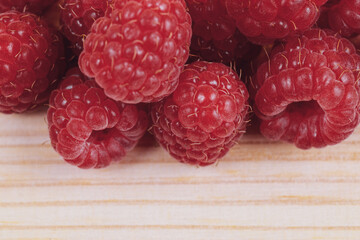 Heap of fresh ripe and sweet raspberries on wooden table. Red raspberries. Macro shot.
