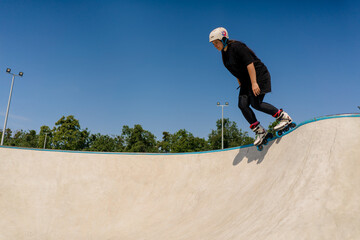 young skilled woman rollerblading and jumping on the ramp in the skate park outside Practicing her tricks or technique of rollerblading for competition