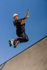 young skilled woman rollerblading and jumping on the ramp in the skate park outside Practicing her...