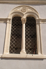 Small medieval arched double window on stone church wall  in Italy