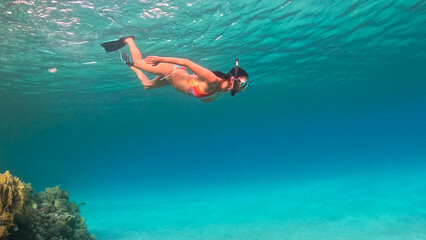 Brunette woman with snorkeling mask and tube swimming in the sea. Underwater view.