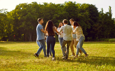 Happy cheerful friends are having fun in the park in summer. Group of joyful young diverse people are enjoying summertime, dancing a round dance and having a good time together