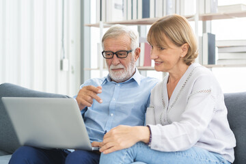 Happy senior couple, elderly family, caucasians mature, adult lover and retired man, woman using laptop computer shopping online, reading news on sofa at home together. Husband and wife lifestyle.