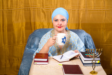 A Jewish woman in a kisui rosh headdress, a teacher of tradition, drinks tea during a break between...