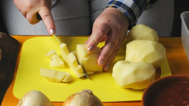 Women's hands are cutting the heartofel with a large knife on a plastic board. close-up