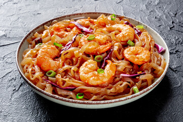 Konjac pasta. Shirataki fettuccine with shrimps and vegetables, a healthy diet dish, on a black stone background