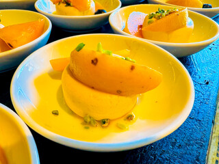 yellow pudding, or semifreddo, or mousse or panna cotta, garnished with apricot slices and pistachios. buffet. at catering event on some festive event, party or wedding reception
