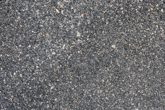 The road surface is strewn with dark gray small crushed granite pebbles. Used for a walkway or as a background image for graphic design work