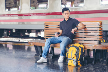 Cheap Travel and Lifestyle concept.Holiday Time,Young Solo Traveler man wearing sneaker and sitting...