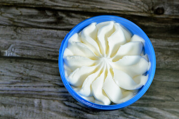 vanilla white frozen ice cream in a plastic bowl isolated on wooden background and ready to be...