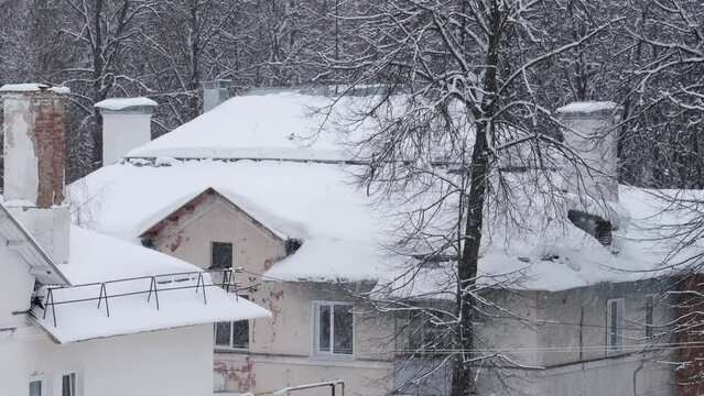pipes on the roofs of old houses in a snowfall on a winter day