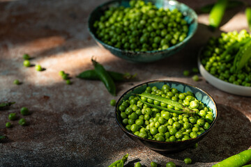 Three bowls with fresh sweet peas on stone surface.