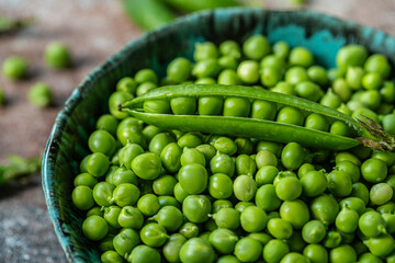 Bowl with fresh garden sweet peas with open pod on the top.