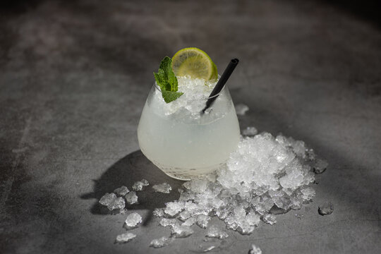Refreshing summer cocktail with mint and lemon in glass full of ice shot in hard light