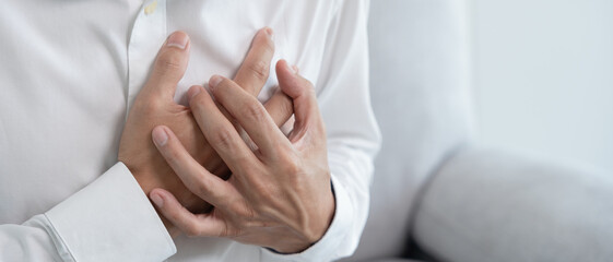 hand hold chest with heart attack symptoms, asian woman have chest pain caused by heart disease, leak, dilatation, enlarged coronary heart, press on the chest with a painful expression