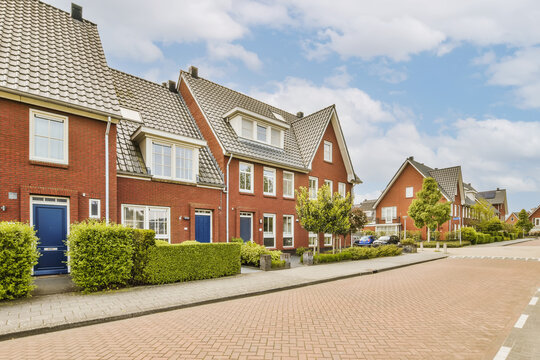 an empty street in the netherlands with red brick houses on either side and blue sky overhead over them all around