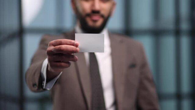 Handsome young man giving business card in modern office