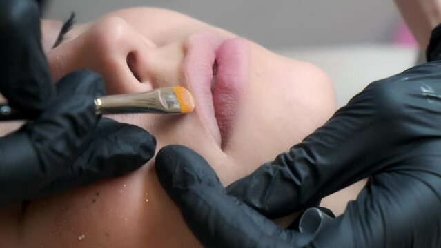 Before the procedure of permanent lip tattooing, marking with a white soft brush along the contour of the lips. The concept of cosmetology.