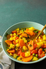 Minestrone soup from zucchini and tomato, onion and carrots, corn and peas with parsley, a plate of soup close-up, vegetarian soup