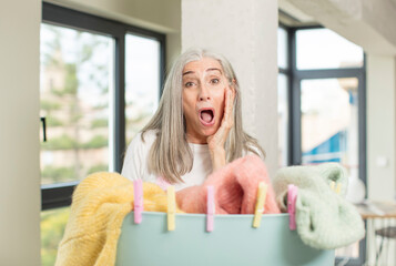 pretty senior woman feeling happy and astonished at something unbelievable. washing clothes concept