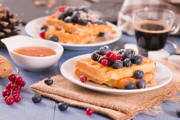 Waffles with red currant and blueberries on white dish. - 624463259