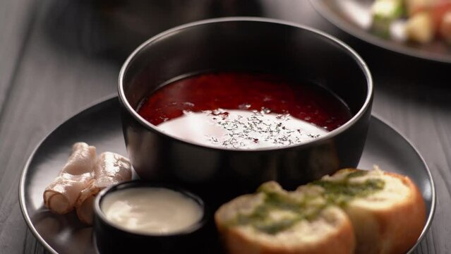 Put sour cream in borscht beetroot soup, the first hot dish with pampushka with garlic