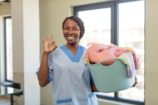 black afro woman feeling happy, showing approval with okay gesture. laundry and housekeeping concept
