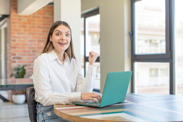 young pretty woman feeling shocked,laughing and celebrating success. working with a laptop