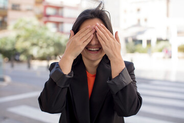 Fototapeta premium pretty woman smiling and feeling happy, covering eyes with both hands and waiting for unbelievable surprise