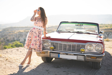 beautiful girl in a retro dress and sunglasses at sunrise happy posing on the background of the...