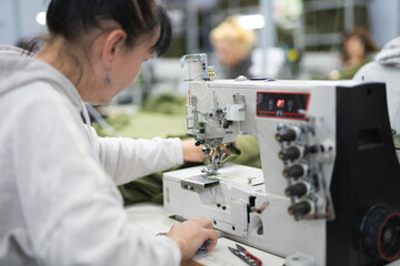 workers in an industrial garment factory sew clothes on sewing machine