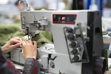workers in an industrial garment factory sew clothes on sewing machine