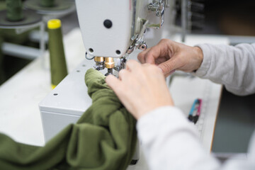 workers in an industrial garment factory sew clothes on sewing machine