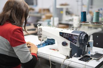 workers in an industrial garment factory sew clothes on sewing machine