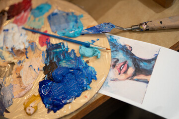 close-up of a brush and a palette with mixed oil paints in an artist's studio